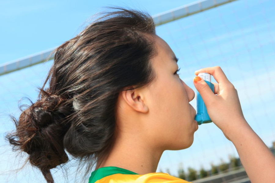 Girl-in-football-tshirt-puffs-an-inhaler.jpg