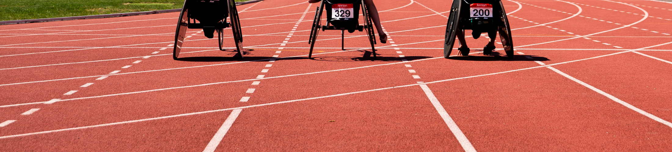 Three wheelchairs line up on an athletics track, ready to race.